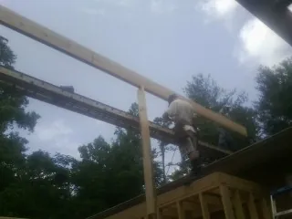 Carpenter setting a ridge beam over a new addition frame — Ice Dam Removal by Roofing Brothers in Dent