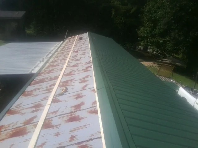 Old rusted panels beside newly installed green metal roofing — Wind Damage Roof Repair by Roofing Brothers in Dent