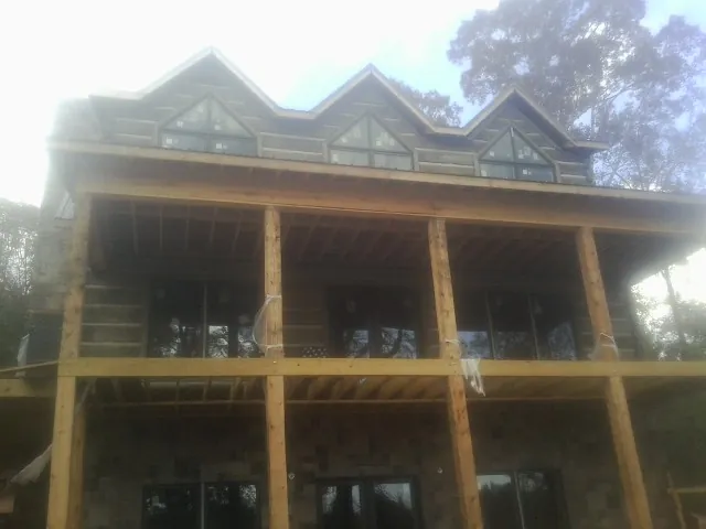 Dormers and porch framing on a large log home under construction — Roof Coating work by our crew in Dent