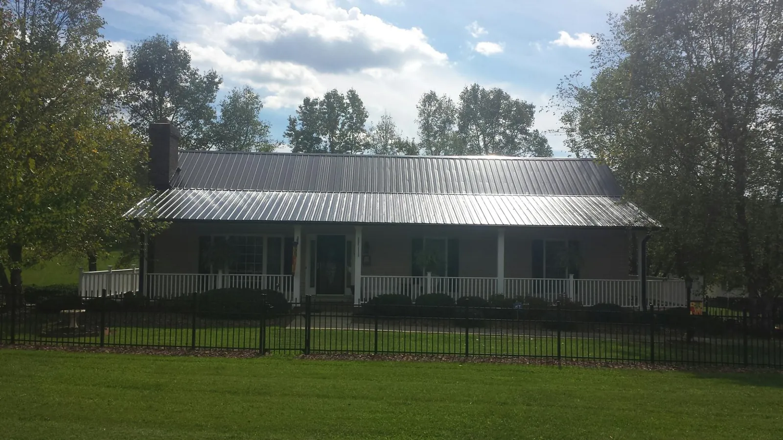 Gray metal roof on a brick ranch with a full width front porch — Gutter Guard Installation work by our crew in Dent