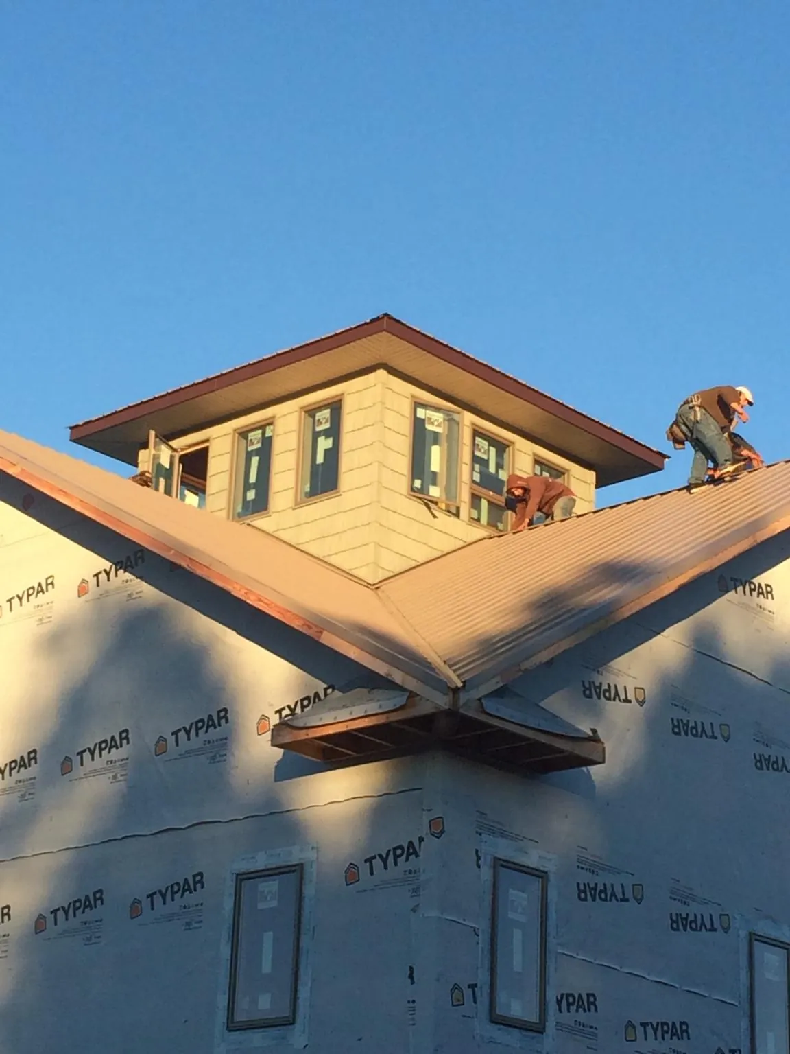 Roofers working around a rooftop cupola on a new metal roof at sunset — Roof Waterproofing in Dent by Roofing Brothers